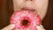 Close-up woman eating a pink donut , delicious, sweet, sweet tooth. Diet. Dieting. Female mouth bites a dessert.