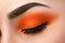 Close-up of woman eye with beautiful orange smokey eyes with black arrow makeup