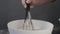 Close-up, woman falling flour in a bowl and mixing ingredients with a whisk