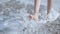 Close up of a woman feet on a sandy beach with sea.