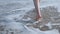 Close up of a woman feet on a sandy beach with sea.