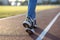 Close up of woman feet in sport sneakers and blue jeans on running lane on outdoor sports court