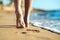 Close up of woman feet walking barefoot on sand leaving footprints on golden beach. Vacation, travel and freedom concept. People