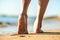 Close up of woman feet walking barefoot on sand leaving footprints on golden beach. Vacation, travel and freedom concept. People