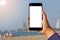 Close-up Woman hand holding mobile phone on beatiful fresh sea sand and blue sky background