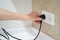 Close up Woman hand insert or pull out elecrticity plug in outlet on the wall