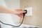 Close up Woman hand insert or pull out elecrticity plug in outlet on the wall