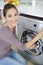 Close-up woman hand loading dirty clothes in washing machine