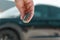 Close-up woman hand presses a button on the car remote control against blur black car
