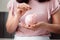 Close-Up Woman Hand is Putting a Money Coin into Piggy Bank on The Bedroom., Female Hand is Inserting Coin in Pink Piggy Saving.