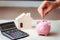 Close-Up Woman Hand is Putting a Money Coin into Piggy Bank on The Bedroom., Female Hand is Inserting Coin in Pink Piggy Saving.