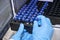 Close up woman hand in a rubber gloves put sample in a glass vial with blue cap into the autosampler rack in HPLC system