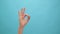 Close up of woman hand showing ok sign okay gesture on the blue background