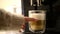 Close-up of woman hand taking a clear glass cup of fresh latte macchiato coffee from modern coffee machine.