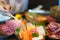 Close up of woman hand uses chopsticks to put salmon sashimi on a plate in a Japanese restaurant