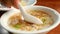 Close up of woman hand using spoon scooping the boiled rice with pork and fried garlic in a white bowl on breakfast.