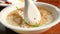 Close up of woman hand using spoon scooping the boiled rice with pork and fried garlic in a white bowl on breakfast.