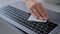 Close up: woman hands cleaning laptop keyboard with wet wipe - slow motion