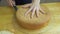 Close up of woman hands cutting baked biscuit for making sweet cake.