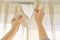 Close up of woman hands hanging curtain with metal hooks on ceiling ledge