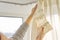 Close up of woman hands hanging curtain with metal hooks on ceiling ledge