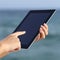 Close up of a woman hands holding and browsing a digital tablet on the beach