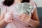 Close-Up Woman Hands is Holding Money Cash and Piggy Bank in Her Bedroom, Pink Piggy Saving, Business Banking and Financial