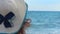 Close-up of woman in hat relaxing on sunny beach at seaside, enjoying seascape