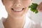 Close up woman with healthy toothy smile holding parsley leaf