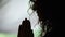 Close-up of woman holding hands in prayer asking God to help, praying silhouette