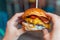 Close up woman holding taste cheeseburger with bacon. Gourmet burger, Fastfood