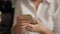 Close up on woman holds a smartphone in her hand while sitting in office making a break in work to enjoy fine coffee and