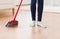 Close up of woman legs with broom sweeping floor