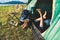 Close up of woman legs relaxing in camping tent with mountain lake and meadow and grass field background. Lifestyles and People