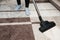 Close up of woman with legs vacuum cleaner cleaning carpet at home