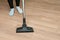 Close up of woman with legs vacuum cleaner cleaning floor at home