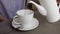 Close-up of woman pour the tea with teapot in cup.