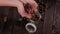 Close-up of a woman pouring a macadamia nut into a jar on a wooden background.