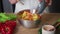 Close-up of a woman preparing vegetables in the kitchen. The hands of an unrecognizable woman sprinkle salt on