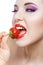 Close up of woman with red lips eating strawberry