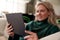 Close Up Of Woman Relaxing On Sofa At Home Using Digital Tablet