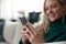 Close Up Of Woman Relaxing On Sofa At Home Using Mobile Phone