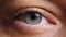 A close-up of a woman's eye with a contact lens looks directly into the camera. The eyelid blinks several times. A