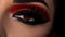 a close up of a woman\\\'s eye with red and black makeup