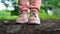 Close up of woman\'s feet in shoes on ground. Woman in pink sneakers stands in park in summertime.
