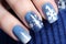 Close up of woman\\\'s fingernails with blue nail polish with seasonal winter snowflakes themed design
