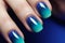 Close up of woman\\\'s fingernails with dark blue and turquoise ombre colored nail polish design