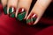 Close up of woman\\\'s fingernails with nail polish with seasonal red and green checkered Christmas themed design