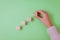 Close-up of woman`s hand completing the wooden cubes series. Green background