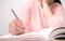 Close up of Woman`s hand drawing a line and writing short summary while reading a book at library